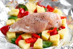 a piece of chicken with pineapples and peppers on aluminum foil