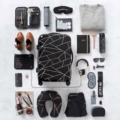 the contents of a travel bag laid out on a white surface, including shoes, sunglasses and other items