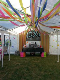 a party tent with colorful streamers hanging from the ceiling and decorations on the walls