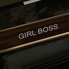 the girl boss sign is on the side of a black and gold car's door