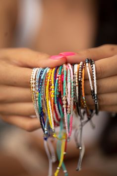 a woman holding a bunch of bracelets in her hands