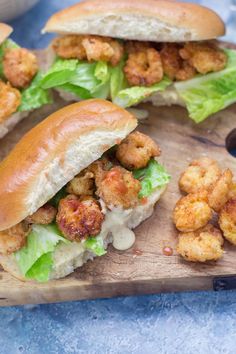 two chicken sandwiches with lettuce and sauce on a cutting board