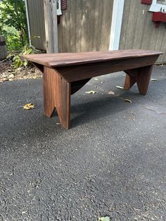 a wooden bench sitting on the side of a road