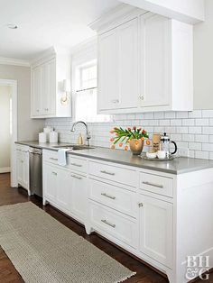 a kitchen with white cabinets and stainless steel counter tops, along with a rug on the floor