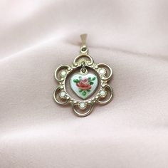 "Lovely vintage gilt sterling silver pendant, made by renowned Norwegian jewellery maker Finn Jensen. Pendant is designed as ornate and enamel adorned round outer part with lovely heart shaped dangle in the middle. Tiny dancing dangle features small rose flower painted on the silver white guilloche enamel background. Finn Jensen began his career in 1944, in partnership at Jensen & Aamodt workshop, and in 1953, he became the sole owner of his Finn Jensen company, as an independent manufacturer of Enamel Locket Jewelry For Anniversary, Victorian Yellow Gold Enamel Necklace, Victorian Style Yellow Gold Enamel Necklace, Enamel Round Pendant Necklace For Anniversary, Yellow Gold Enamel Flower Pendant Jewelry, Anniversary Enamel Round Pendant Necklace, Elegant Enamel Heart Pendant Jewelry, Yellow Gold Enamel Jewelry With Flower Charm, Victorian Gold Enamel Necklace