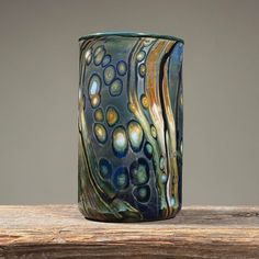 a blue glass vase sitting on top of a wooden table next to a gray wall