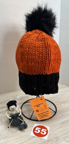 Cozy, handmade, winter hat/beanie, is ready-to-ship and ready-to-wear.  This orange and black beanie features a 5-6" black, faux fur, removable PomPom.  Made of a fine wool blend yarn, this beanie must be hand washed and dried flat to preserve its softness and durability.  The hat measures 8.5" across and 9.5" tall allowing the wearer to pull it down over the ears or roll it up depending on the required warmth.  As with any handmade item, minor flaws and imperfections are inherent to its construction which adds a unique charm to the finished piece. Winter Orange Hat, One Size Orange Winter Hat, Handmade Orange Beanie Hat, Orange Knitted One-size Hat, Yellow Hand-knitted Winter Beanie, Black Beanie, Winter Hats Beanie, Hat Beanie, Black Faux Fur