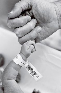 an older person holding a baby's hand with a tag on the end of it