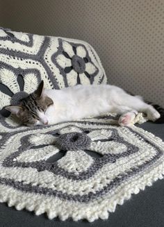 a cat laying on top of a crocheted blanket