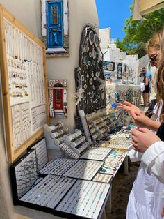 two women looking at jewelry on display in front of a building with blue doors and windows