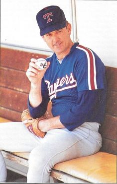 a baseball player sitting on a bench holding a ball