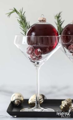 two glasses filled with red wine sitting on top of a black tray next to chocolates