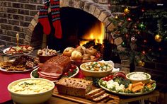 a table topped with lots of food next to a fire place covered in christmas stockings