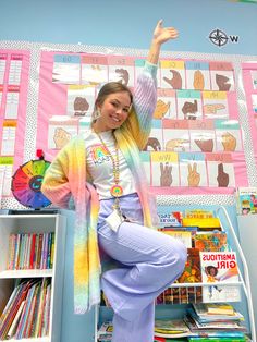 a woman sitting on top of a bookshelf in front of a book shelf