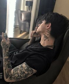 a man sitting in a chair with tattoos on his arm