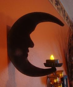 a candle that is sitting in front of a crescent shaped wall hanging on a wall