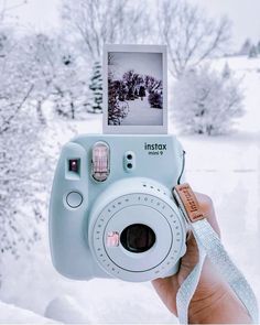 a person holding up a polaroid camera in the snow