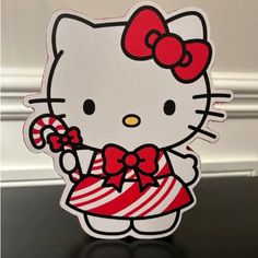 a hello kitty sticker with candy canes in her hand on a black table