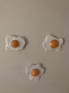 three fried eggs are arranged in the shape of an animal's face on a white surface