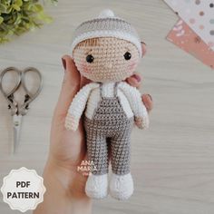 a crocheted doll is being held up by someone's hand next to scissors