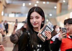 a woman holding up two cell phones in front of her and smiling at the camera