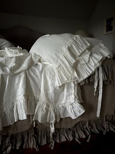 an unmade bed with ruffles and sheets on it's headboard