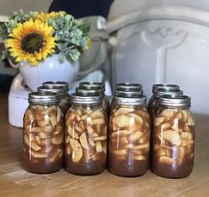 four jars filled with food sitting on top of a table next to a sunflower