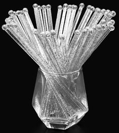 a clear glass vase filled with lots of small crystal sticks on top of a black surface