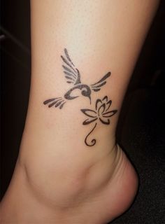 a small tattoo on the foot of a woman with a bird and flower design around it