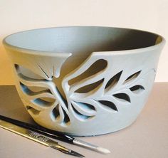 a white bowl sitting on top of a table next to a pen and paper holder