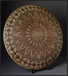 a brown and black plate with designs on the inside, sitting on a stand in front of a dark background