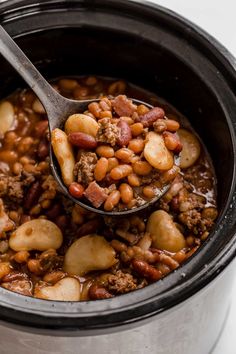 a spoon full of beans and meat in a slow cooker