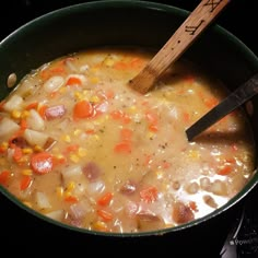 a pot filled with soup sitting on top of a stove next to a wooden spoon