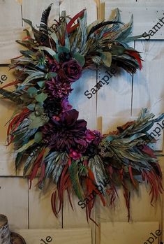 a wreath with feathers and flowers hanging on a wall