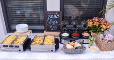 a buffet table with different types of food and drinks on it in front of a window