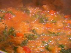 a pot full of soup with carrots, spinach and other vegetables in it