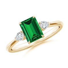 an emerald and diamond ring with three diamonds on the band, set in yellow gold