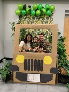 two people and a child in a cardboard jeep