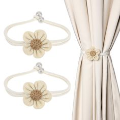 two white curtains with flower clips attached to them