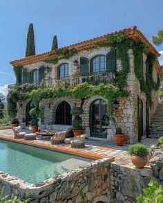 an outdoor swimming pool in front of a stone house with ivy growing on the roof