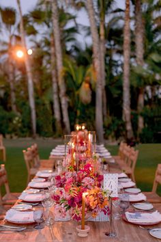 an outdoor dinner table set with candles and flowers