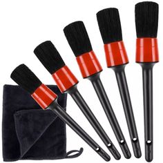 five black and red brushes are next to a pouch with a towel on it,