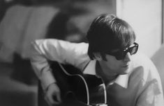 black and white photo of man with sunglasses playing guitar