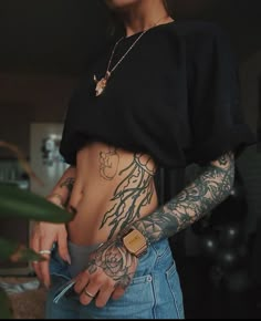 a woman with tattoos on her stomach holding a knife