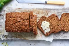 sliced loaf of bread with butter on top and knife next to it sitting on a piece of parchment paper