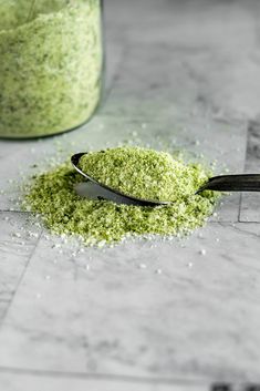 a spoon full of green powder next to a jar