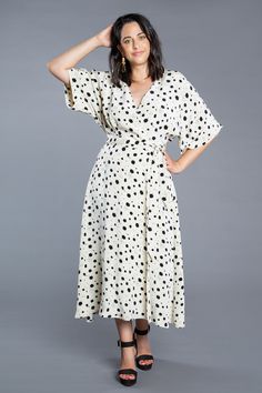 a woman in a white dress with black polka dots on it, posing for the camera