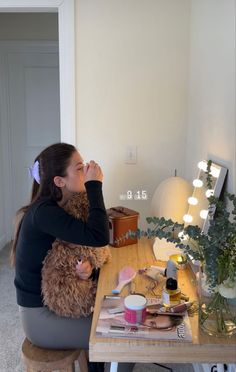 a woman sitting at a table with a stuffed animal in her lap and looking into the mirror