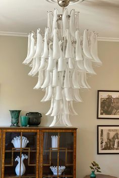 a white chandelier hanging from the ceiling in a room with pictures on the wall