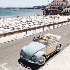 an old car is parked on the side of the road next to the ocean and beach